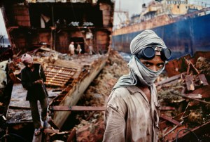 Bombay/Mumbai, India, 1994, INDIA-10207. Welder in a ship-breaking yard. Vessels from around the world end up in this Bombay/Mumbai ship-breaking yard to be broken down into scrap. This worker is one of the many that reduce these colossal ships to tons of valuable iron. It is a dirty and dangerous job. Before turning to his next task, this worker's eyes catch McCurry's camera. Magnum Photos, NYC5952, MCS1993006 K030. From the tangle of deconstruction in the shipbreaking yard of Bombay, a young welder stepped forward in 1994 to engage the camera. His eyes, redoubled by the goggles on his forehead, draws our gaze away from the ship's empty hold and we wonder about this young man, whose face we cannot read fully, whose head is protected only by the cloth that covers his mouth. The promise of our gaze meeting, through a photograph, the look of another across time, and vastly different spaces is one of the signature strengths of McCurry's art. Bannon, Anthony. (2005). Steve McCurry. New York: Phaidon Press Inc., 27. National Geographic Magazine. Vol. 188, No. 3, pgs.56-57, March 1995, Bombay: India's Capital of Hope. Phaidon, 55, Portraits, South Southeast, Iconic Images, final book_iconic, iconic photographs Goggles and scarf shield this worker from the choking dust and smoke of the ship breaking yard. Old ships are brought from all over the world to be cut up for scrap metal. National Geographic: John McCarry (March 1995) Bombay: India's Capital of Hope, National Geographic. (vol.187 (3)) pp.42-67 Portraits_Book South Southeast_Book Steve Mccurry_Book Iconic_Book PORTRAITS_book Untold_book PORTRAITS_APP final print_MACRO final print_Sao Paulo final print_Birmingham India_Book retouched_Sonny Fabbri 02/26/2015